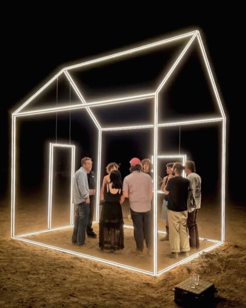 Group of people inside a glowing geometric house structure on a dark background.