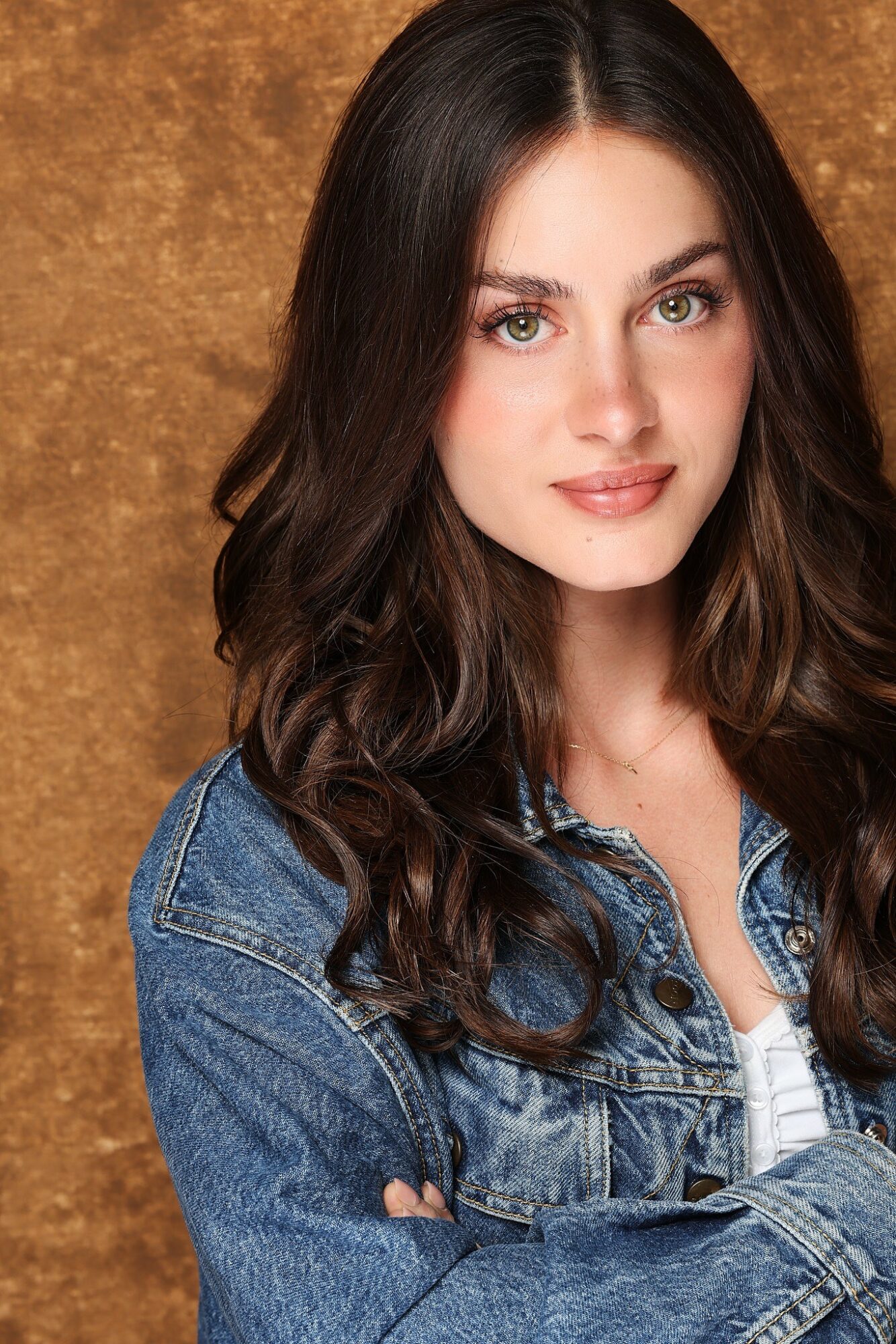 Young woman with long dark hair, wearing a denim jacket, looking at camera with a slight smile.