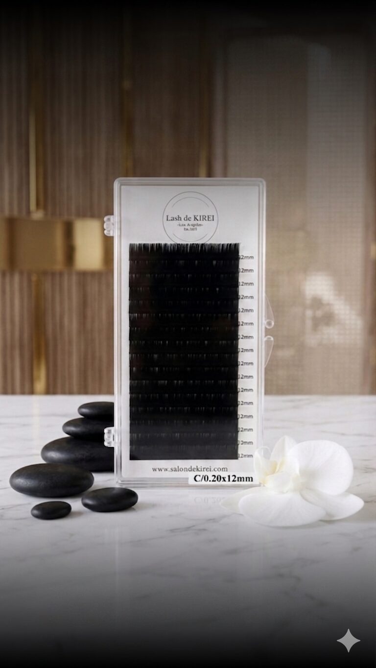 Black eyelash extension tray with black stones and white flowers on marble surface, wooden background.