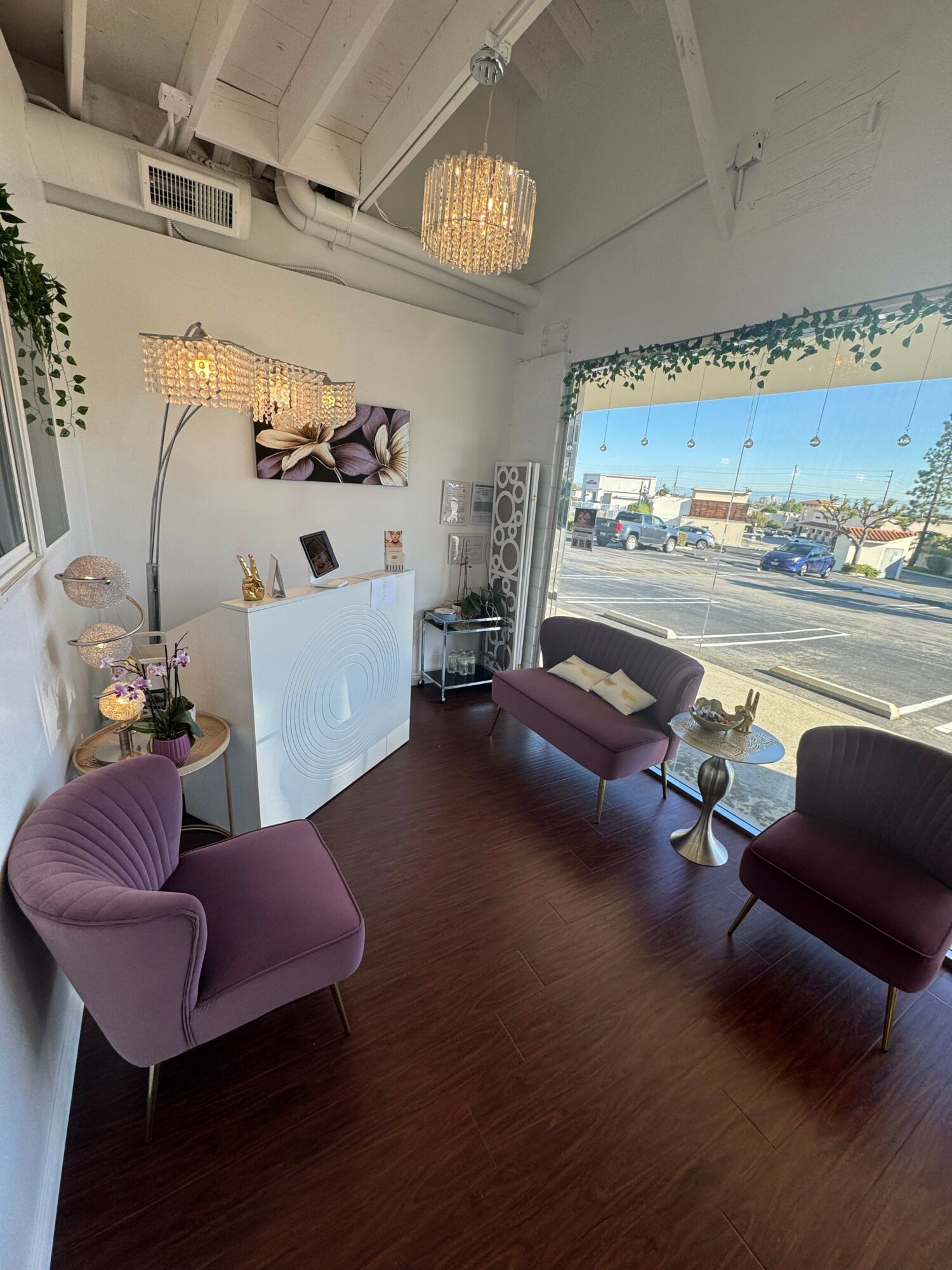 Interior of a waiting area with purple chairs, a white reception desk, and a large window showing a parking lot.