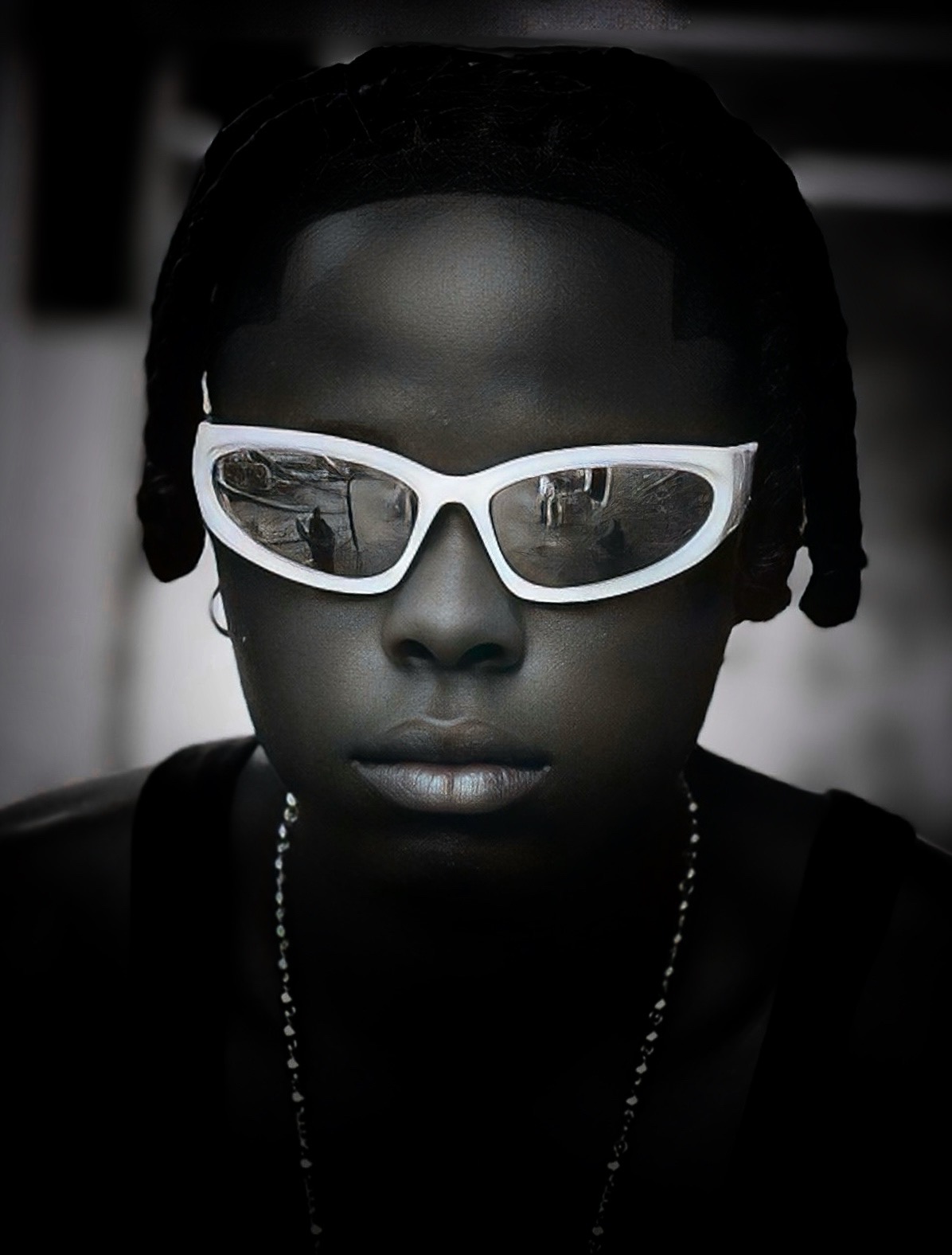 Close-up of a person with dark skin, wearing white sunglasses and a necklace, with braided hair.