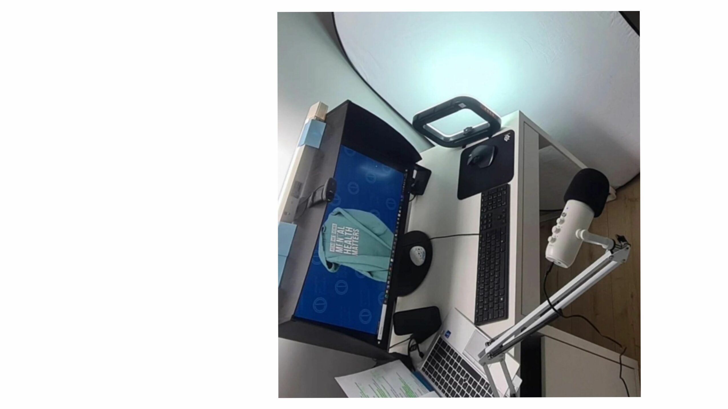 Desk with a laptop, microphone, and a device with a screen displaying a blue interface.