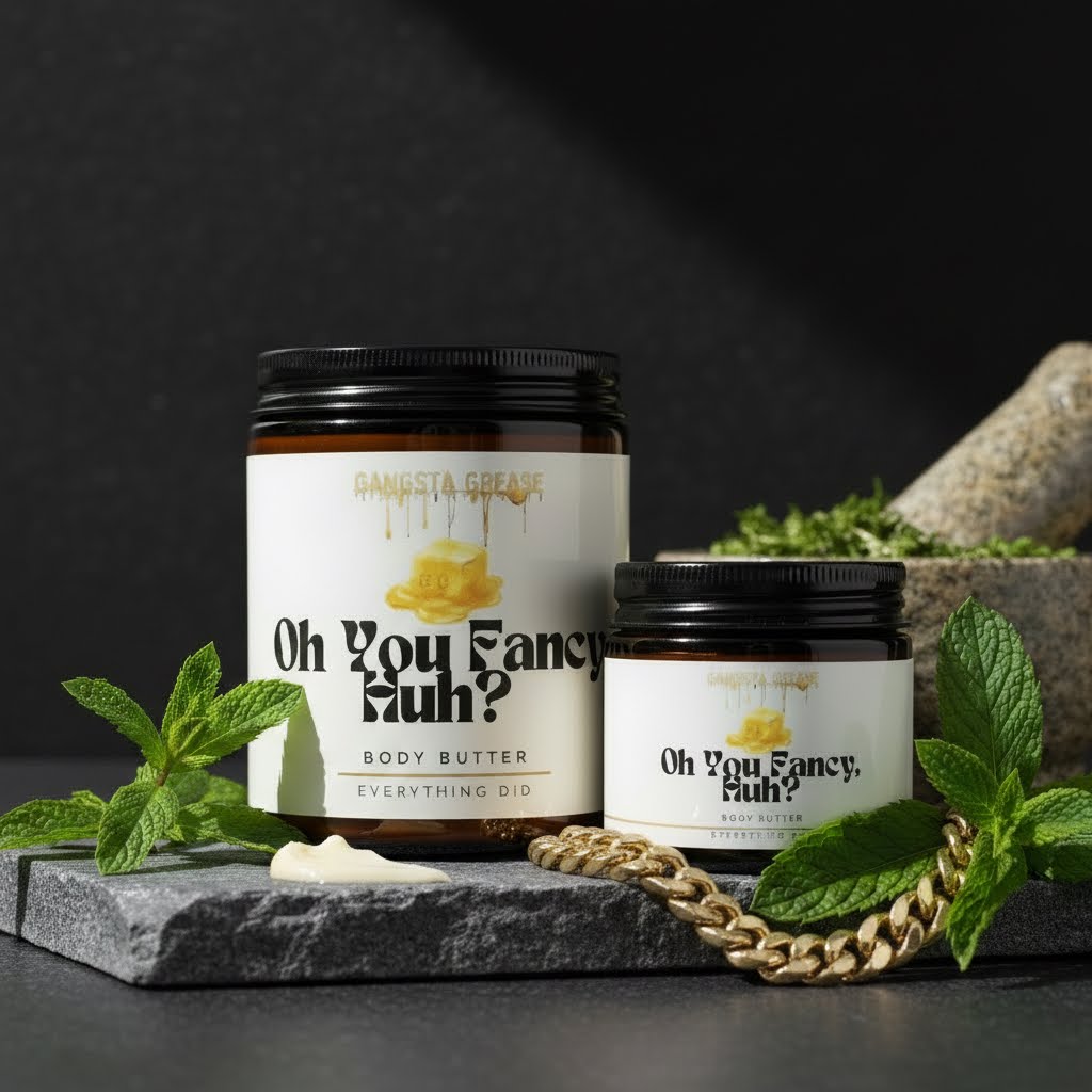 Two containers of body butter on a black surface with green leaves, a chain, and a rock, against a dark background.