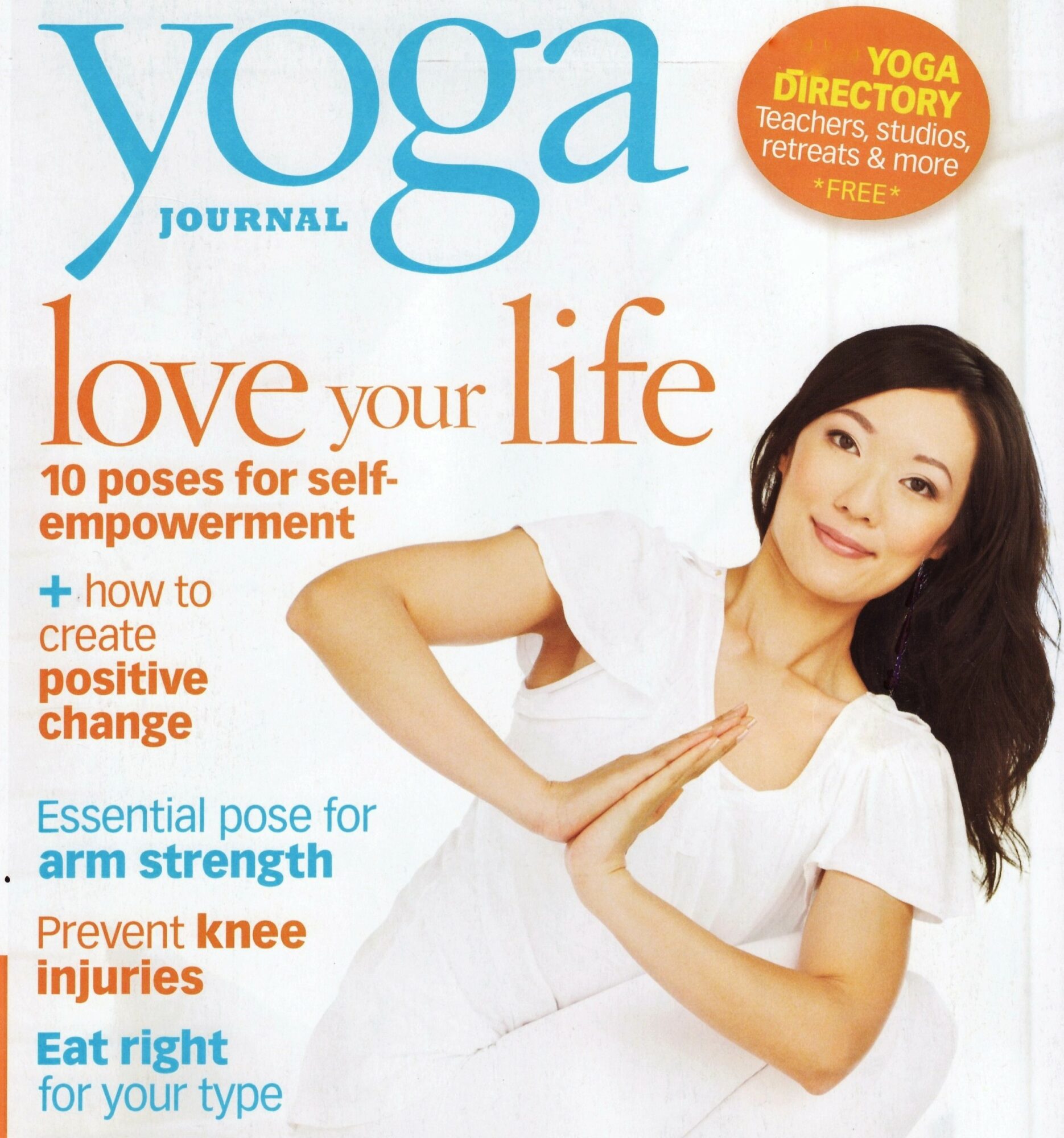 Woman in white shirt demonstrating a yoga pose with hands together, smiling, against a white background.