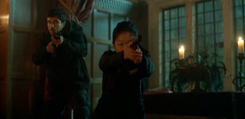 Two children holding guns indoors with candles and large windows in the background.