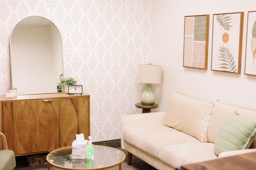 Living room with a white sofa, green pillow, wooden sideboard, mirror, and framed artwork on the wall.