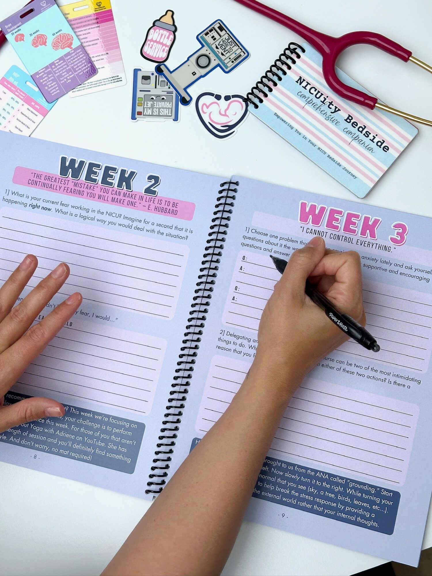 Open planner with weekly pages, a hand writing, medical items, and stickers on a white surface.