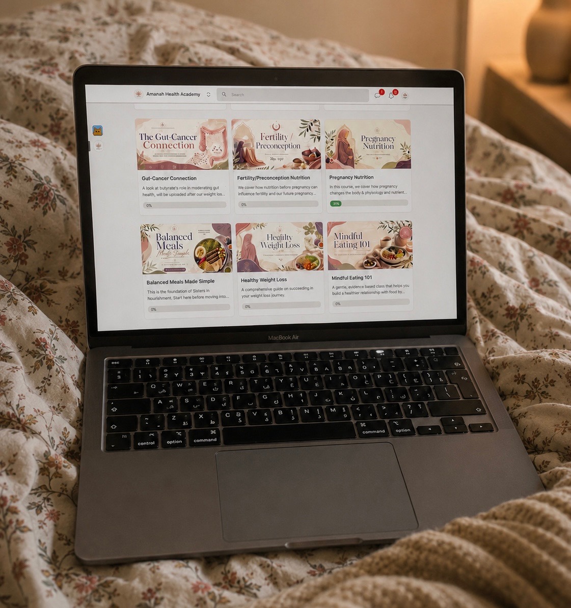 Laptop on bed displaying a webpage with food images and text, bedspread with floral pattern, warm lighting in background.