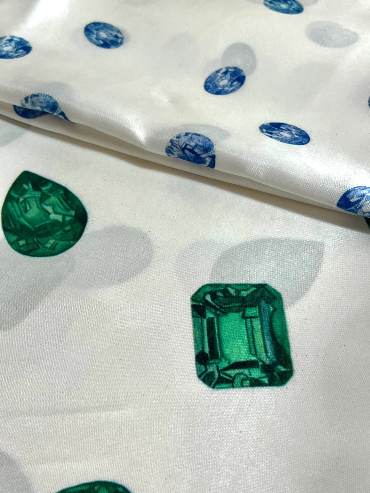 Green gemstone and paper with blue circular patterns, with a shadow on a white surface.