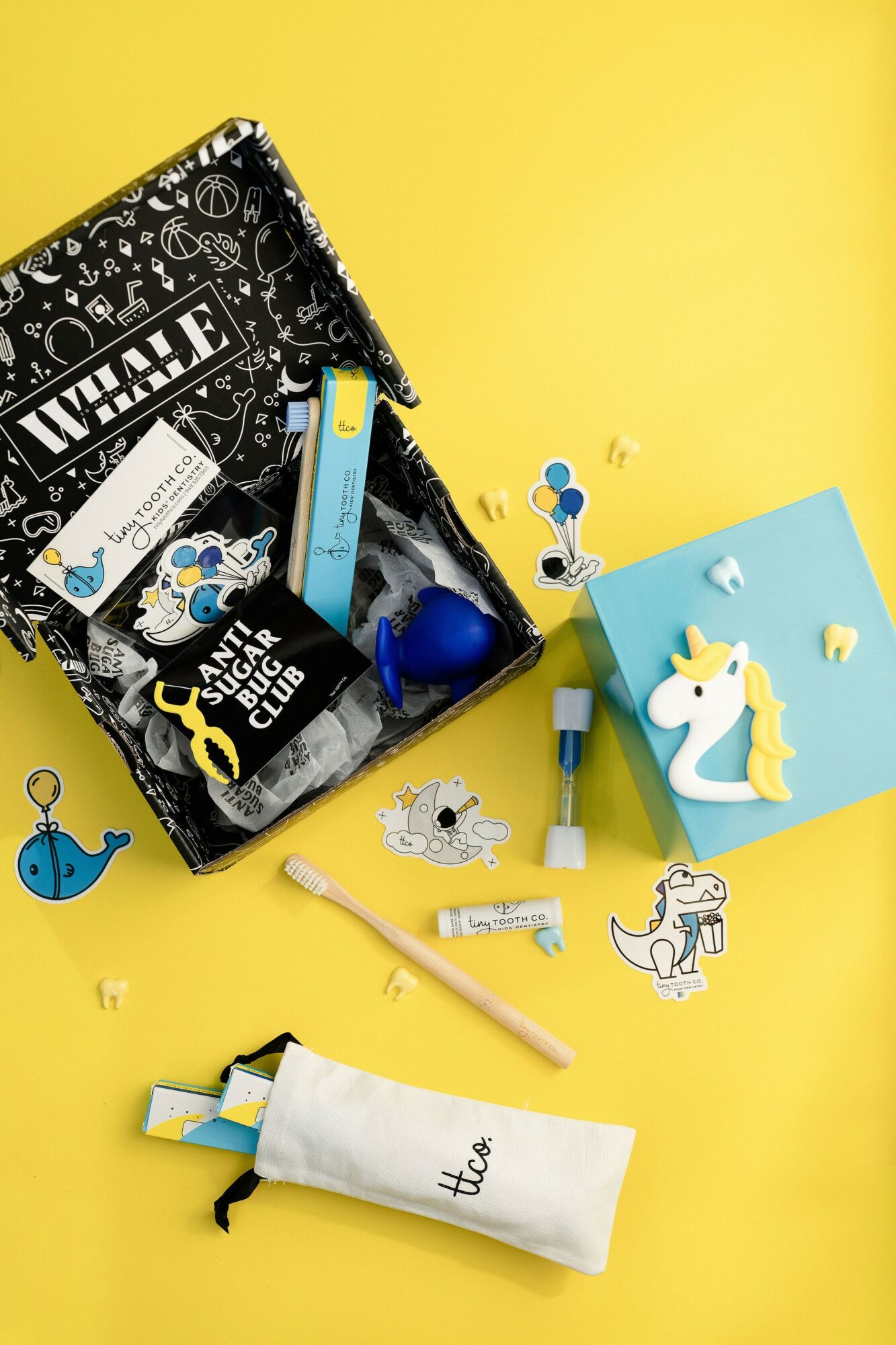 Open box with stationery, a unicorn figure, and paper cutouts on yellow background.