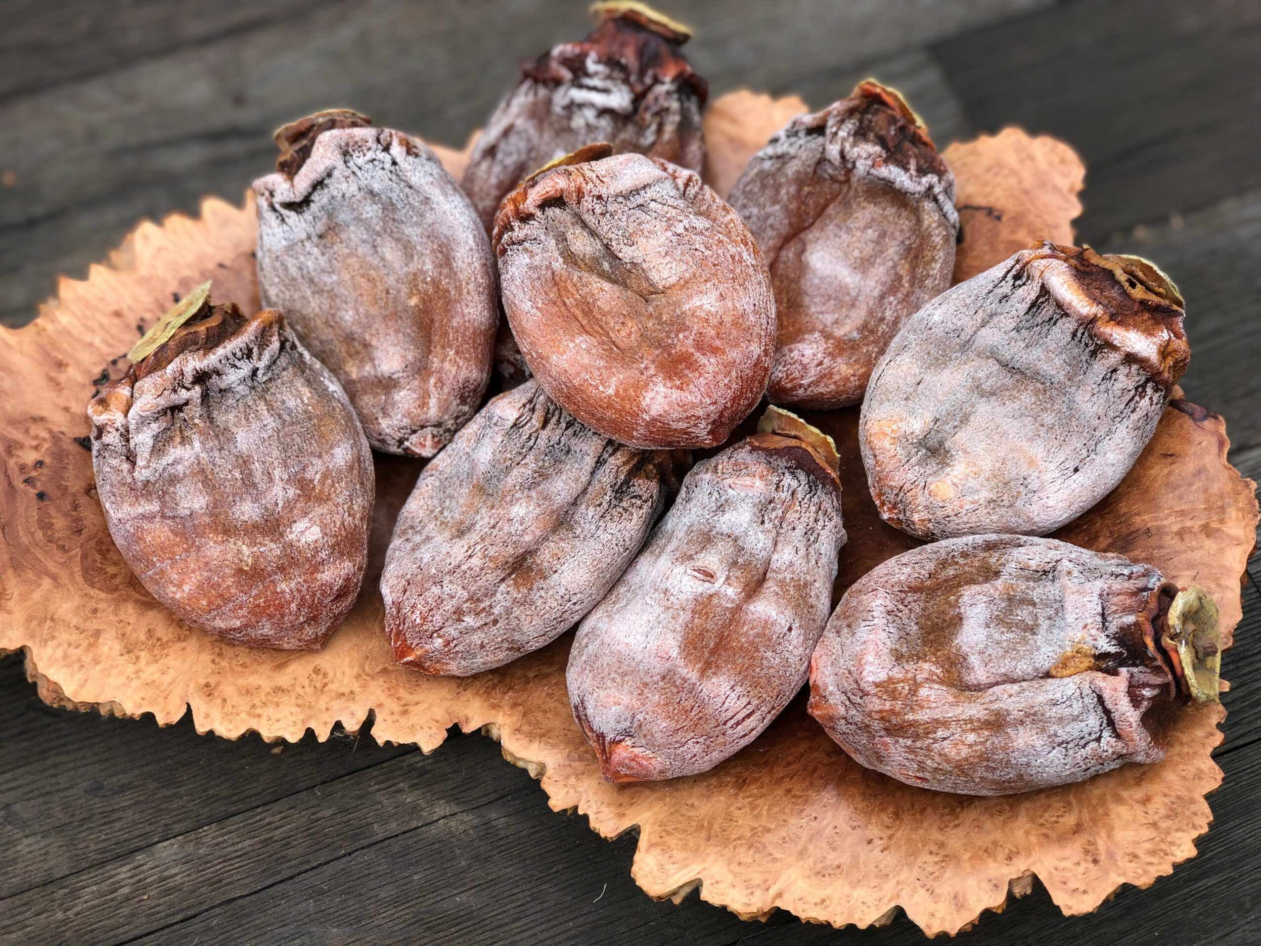 Figs on a leaf, with some dust or powder on them, placed on a dark surface.