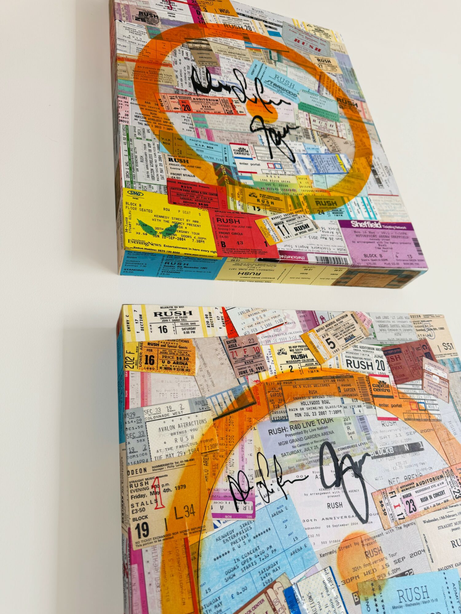 Two mixed media artworks on canvas with colorful ticket stubs, orange heart shapes, and handwritten words, hung on a white wall.