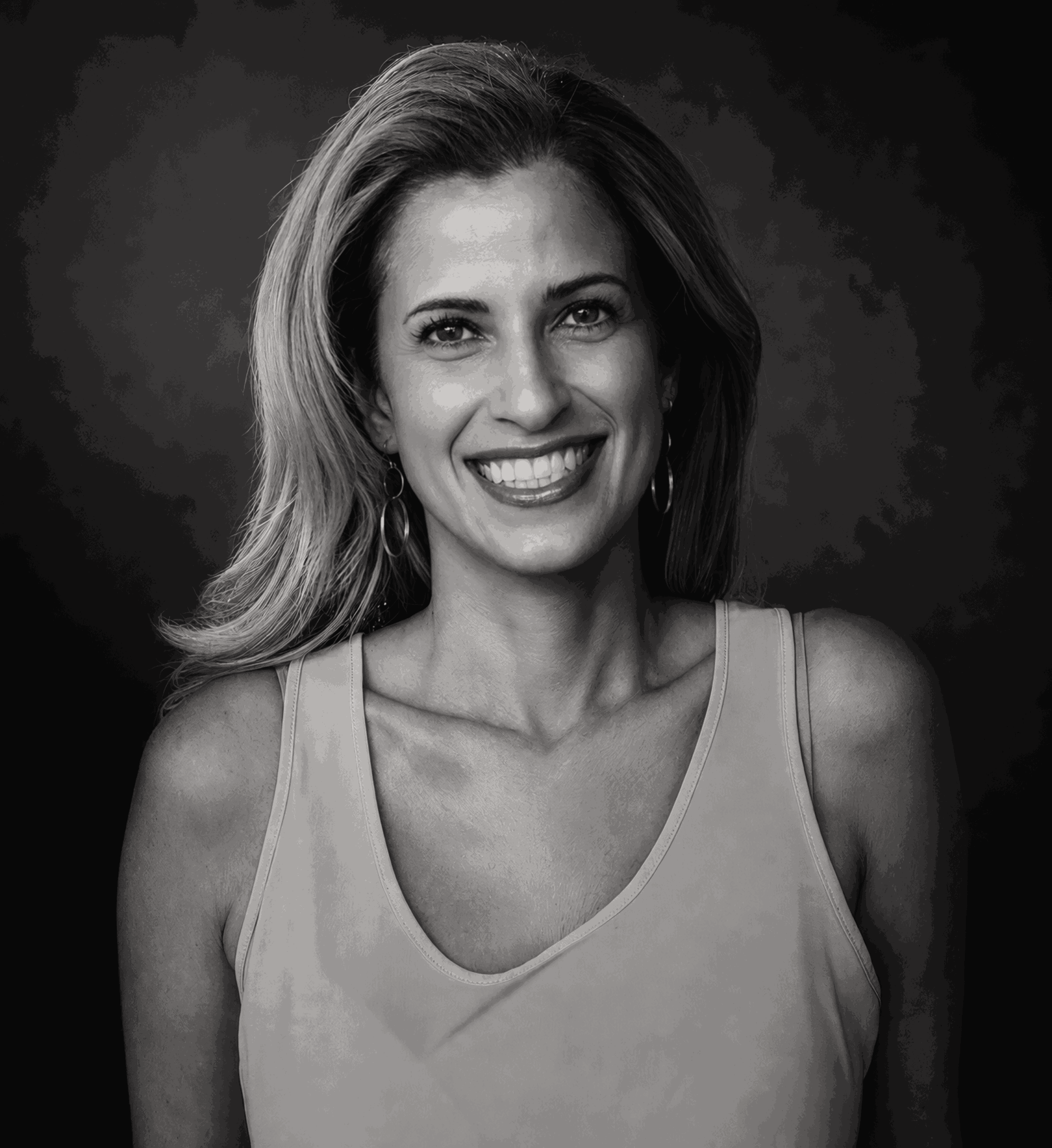 Woman with shoulder-length hair smiling, wearing a sleeveless top, in black and white.