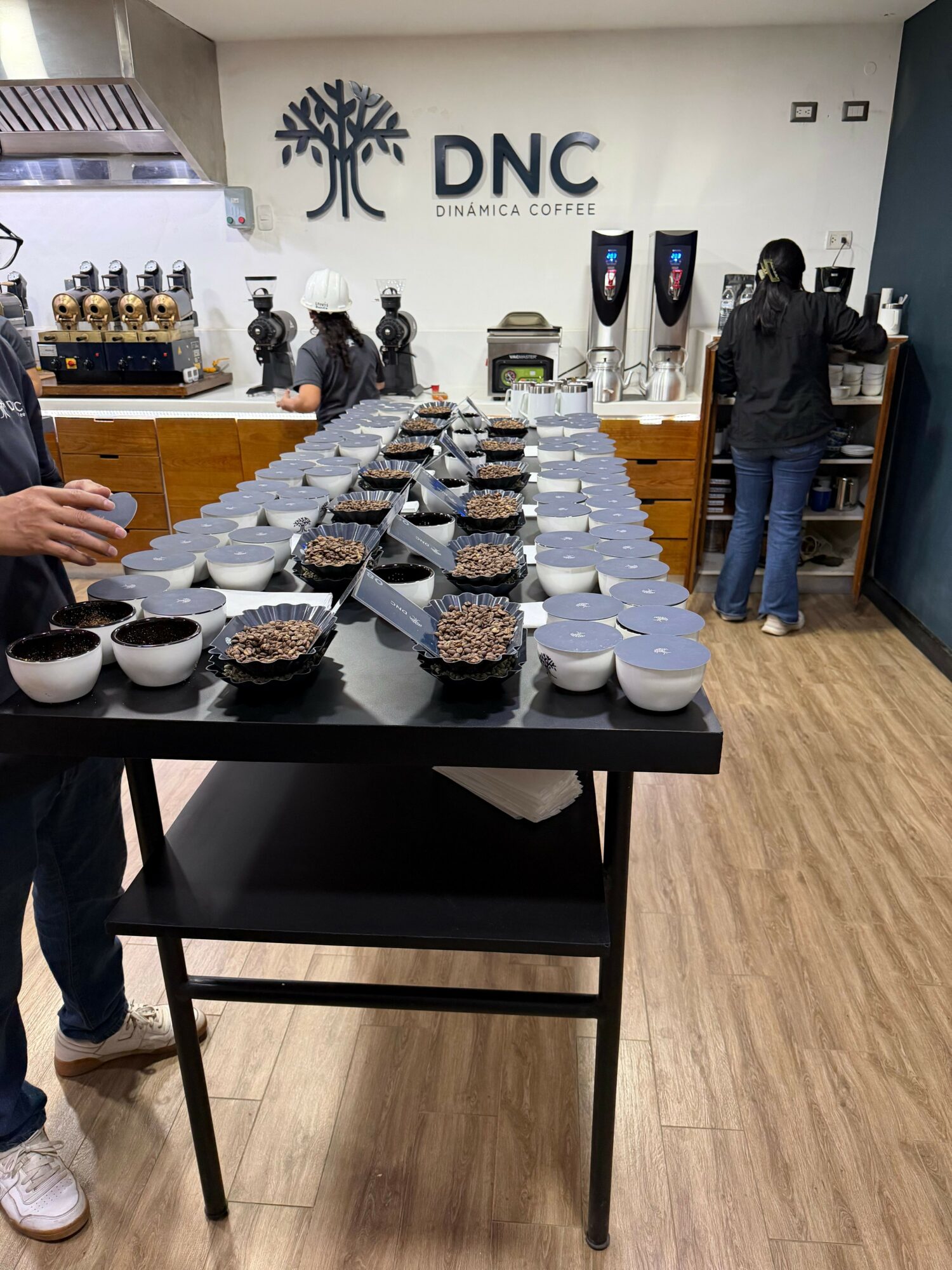 Table with multiple plates of food in a room with a DNC sign on the wall, people in the background, wooden floor.
