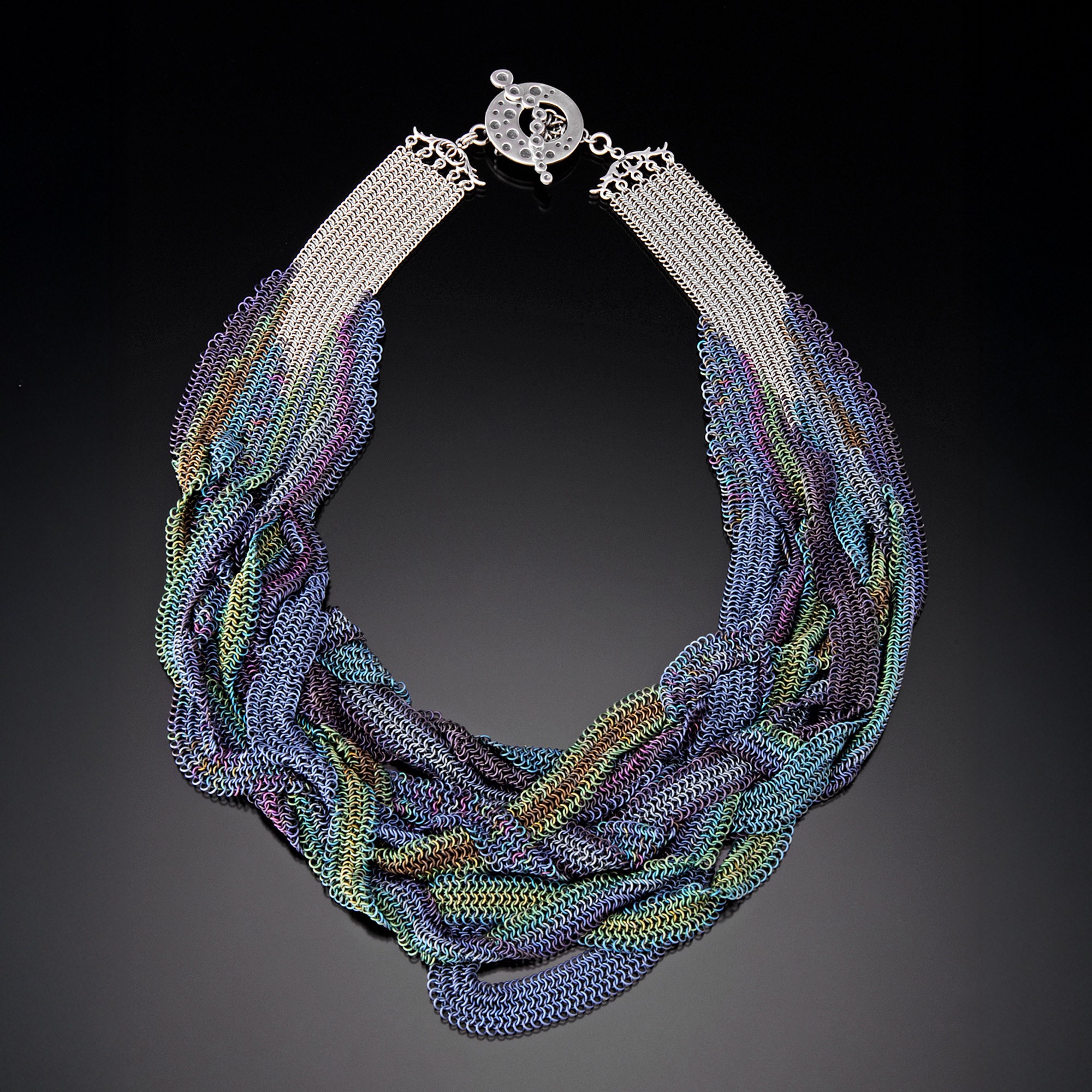 Colorful multi-strand beaded necklace with a circular clasp on a black background.