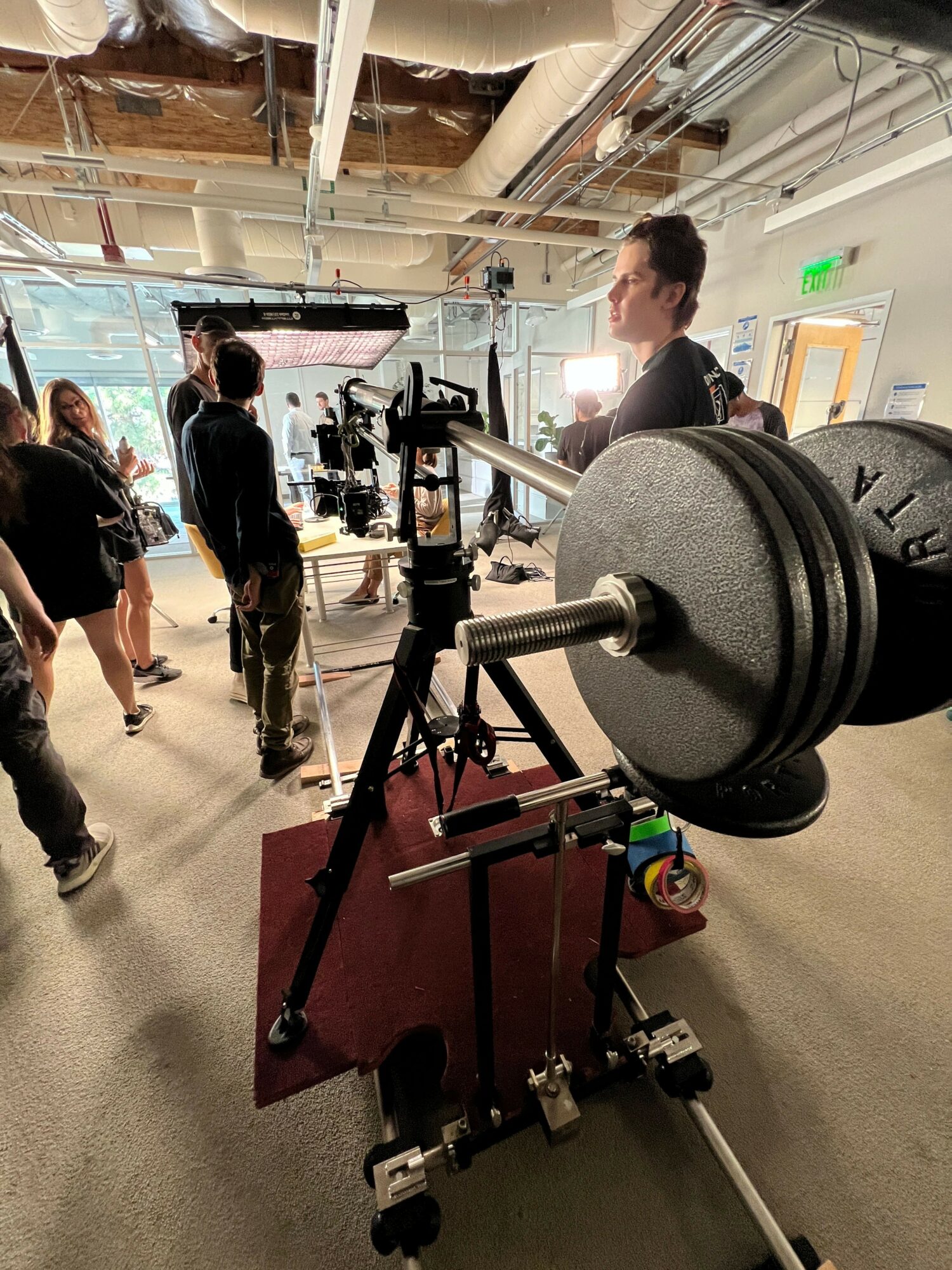 People in a gym with weightlifting equipment and a person lifting weights on a machine.