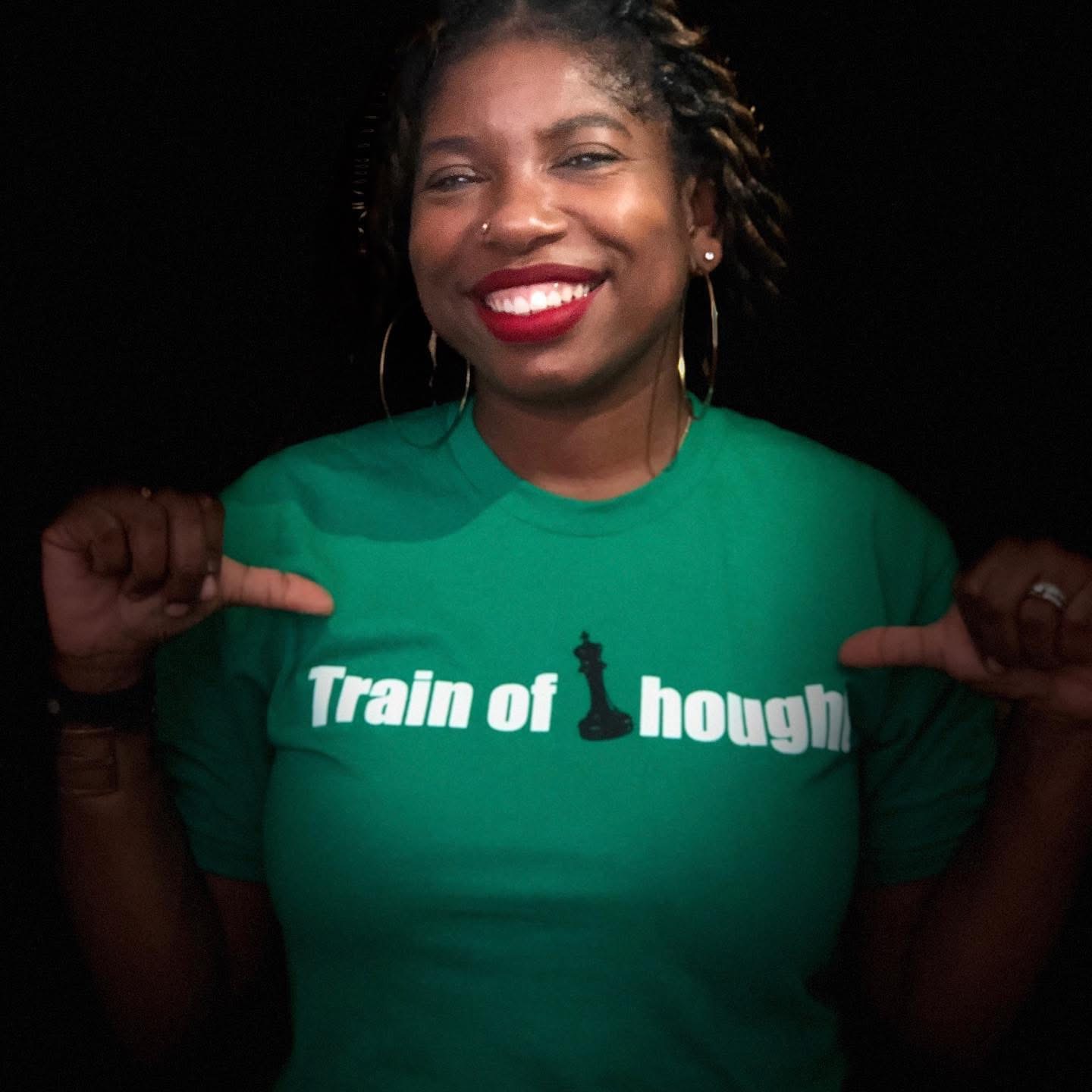 Smiling woman with curly hair wearing a green shirt pointing to the text, against a black background.