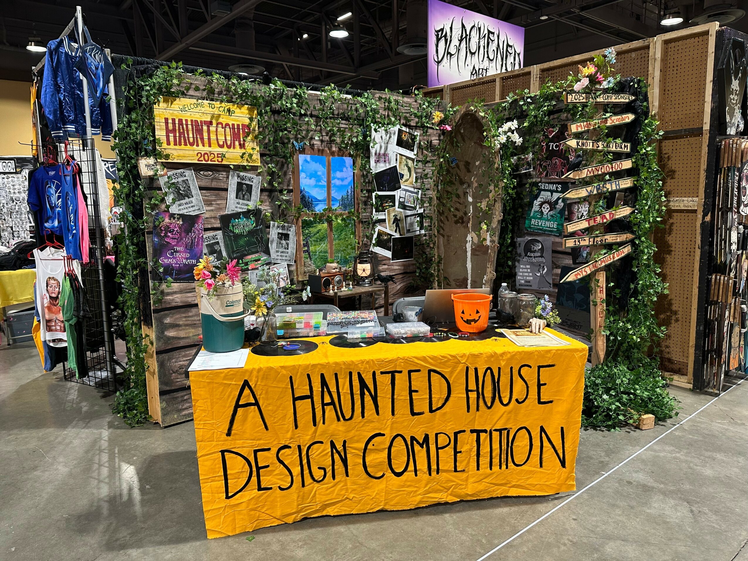 Booth with Halloween decorations and a yellow sign reading 'A Haunted House Design Competition' at an indoor event.