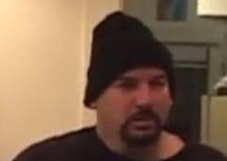 Man wearing a black beanie and dark shirt indoors, with a neutral expression.