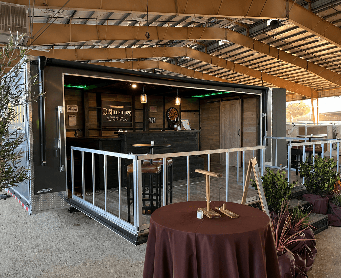 Outdoor bar with seating area, wooden roof, and a round table with a brown tablecloth in front.