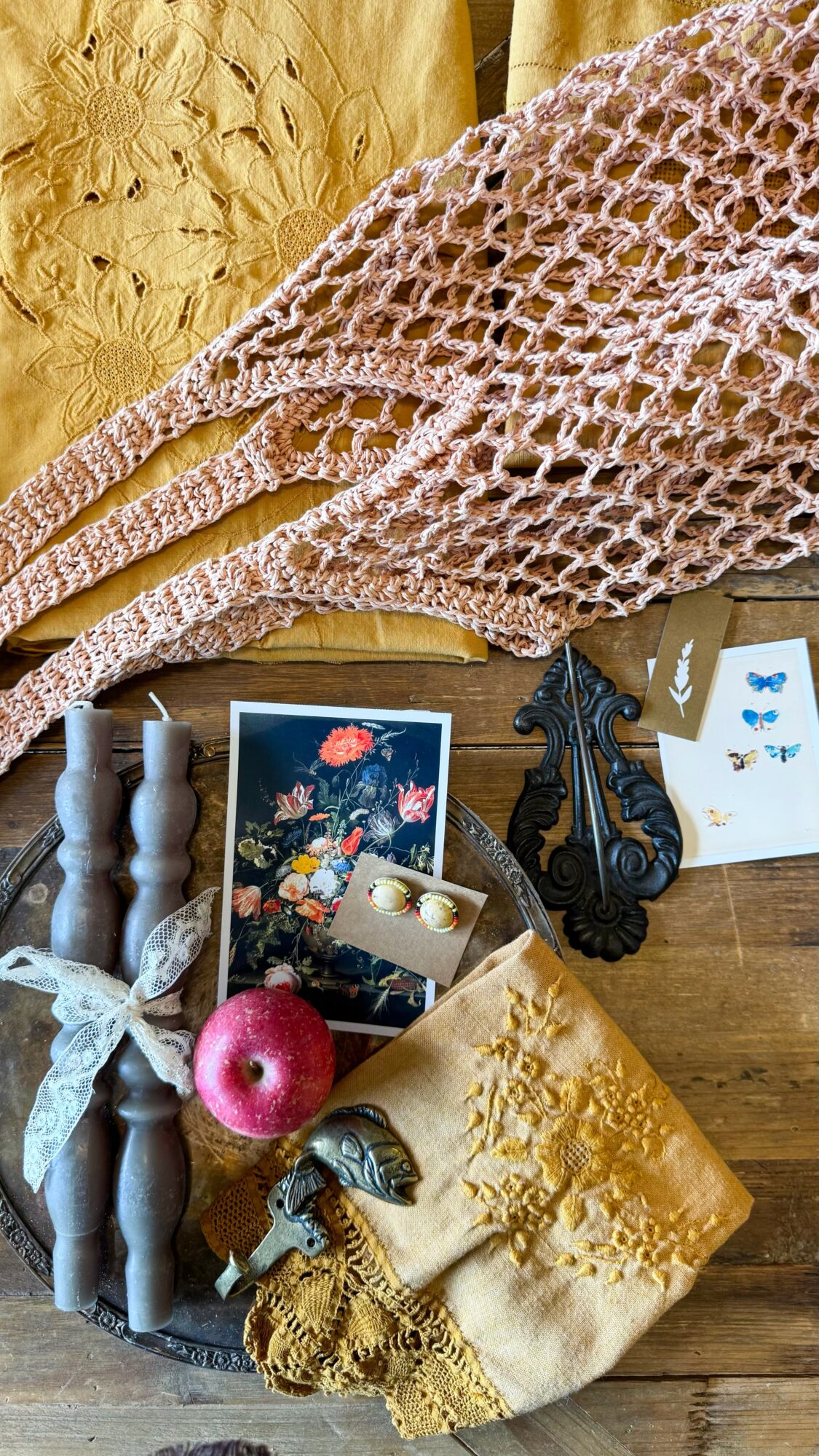 Flat surface with yarn, knitting needles, a pink apple, a small box of jewelry, and decorative items.