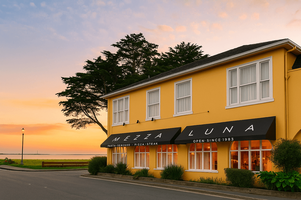Yellow building with black awning, trees, and sunset sky in background.