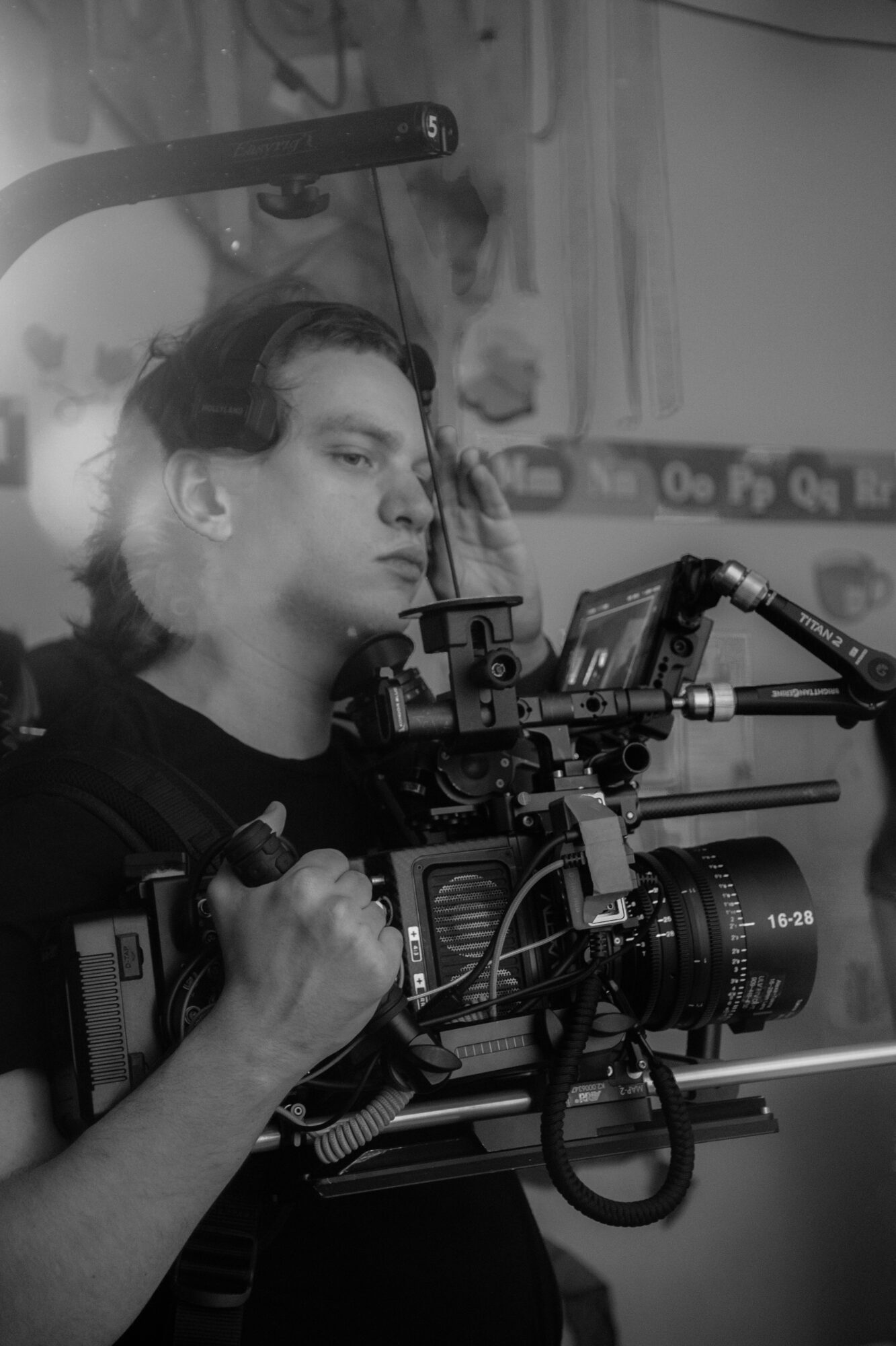 Person operating a professional camera with a microphone attached, indoors, with a blurred background.