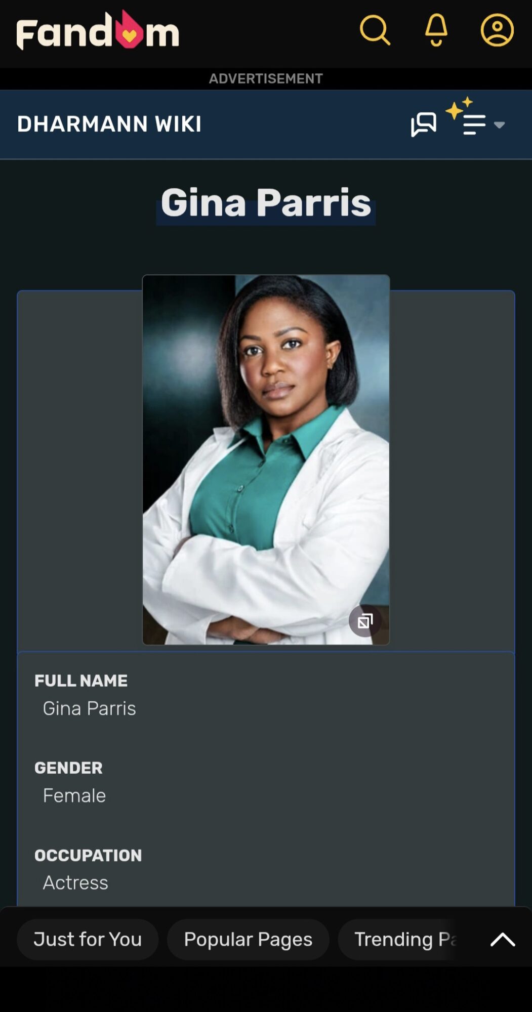 Portrait of a woman with dark hair wearing a teal shirt and white blazer, arms crossed, looking at the camera.