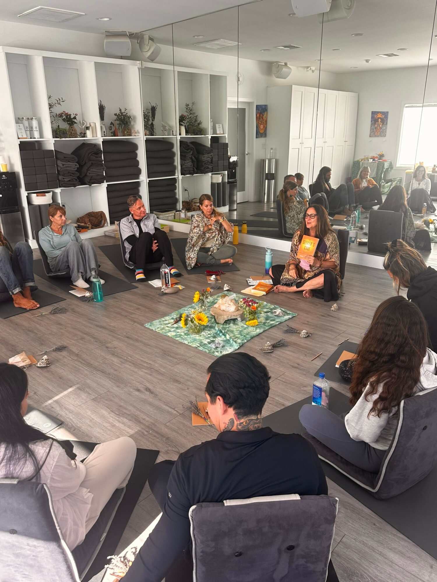 People gathered around a table with food and drinks in a bright, modern room with white walls and shelves.