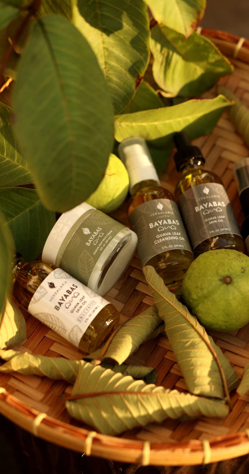 Skincare products and a green fruit arranged on a woven basket with green leaves around.