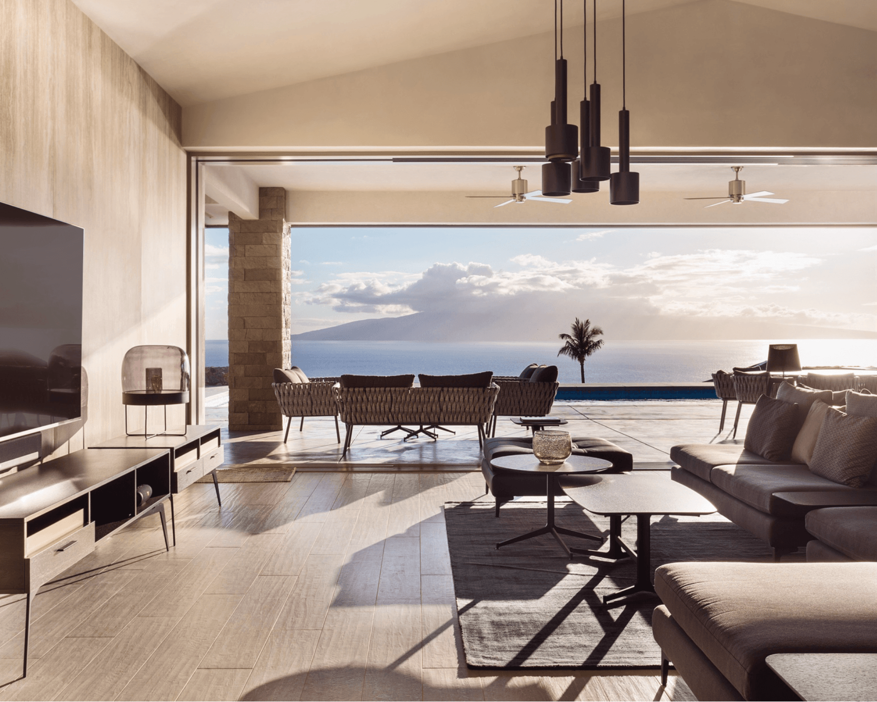 Living room with large window view of ocean, sofa, coffee table, and modern lighting fixtures.