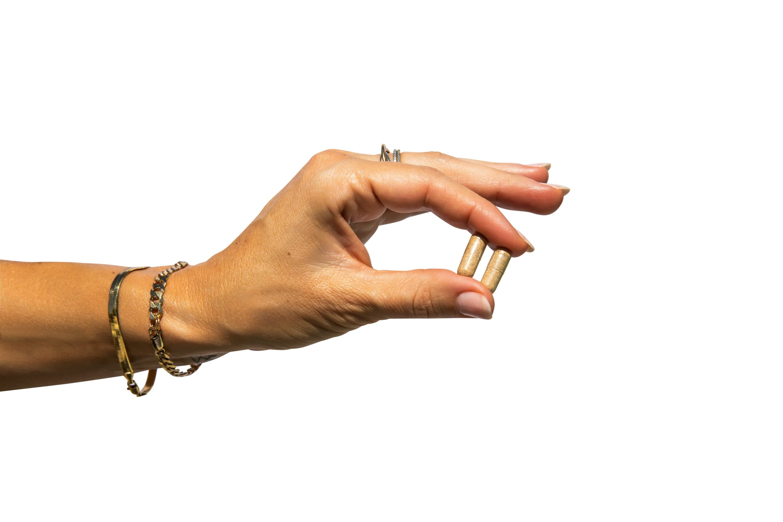 Hand holding a small object with jewelry on wrist and fingers, against a white background.