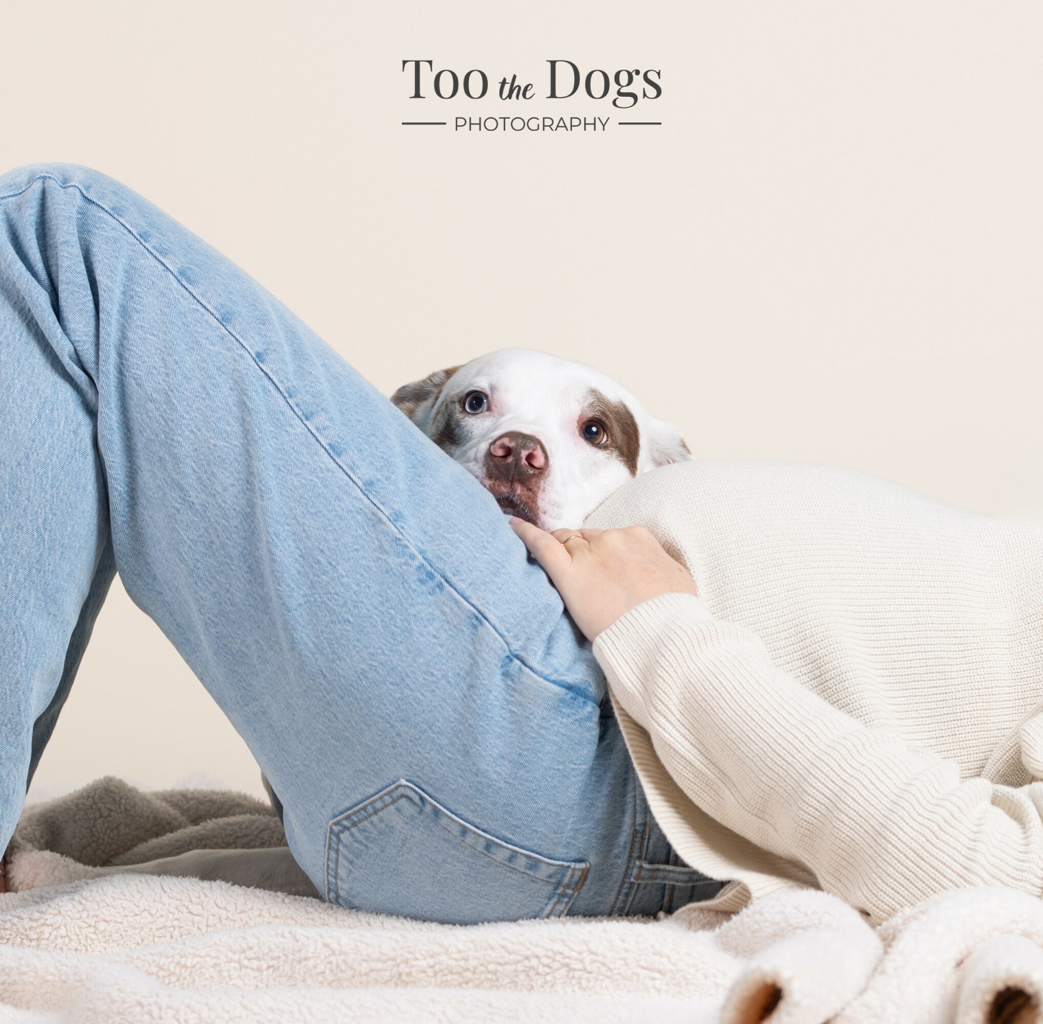 Person lying on their side with a dog resting its head on their lap, against a plain background.