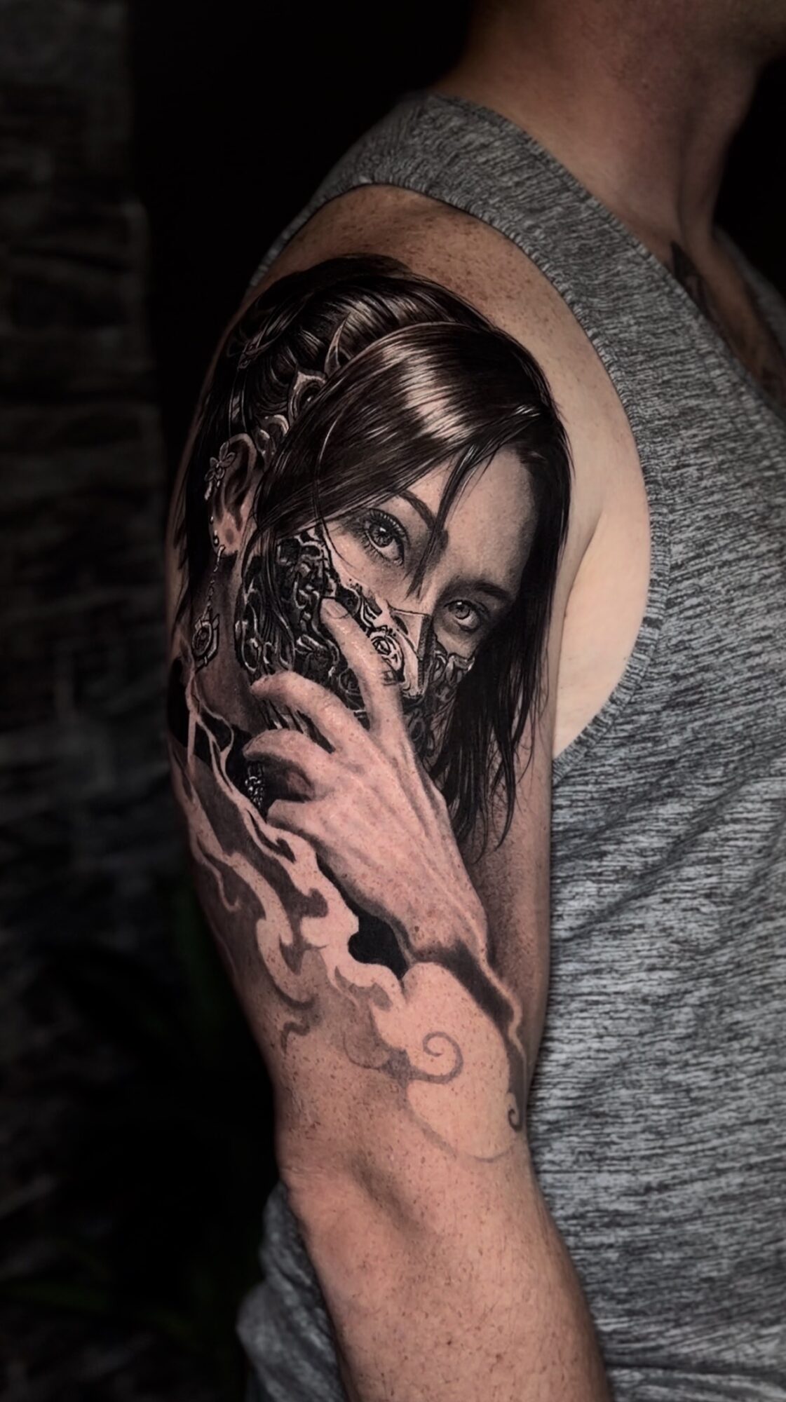 Tattoo of a woman's face with long hair and a hand covering her mouth on person's upper arm.
