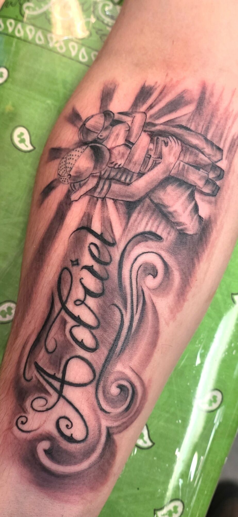 Tattoo of a bee and honeycomb with the name 'Tatiel' in cursive script on a person's arm.