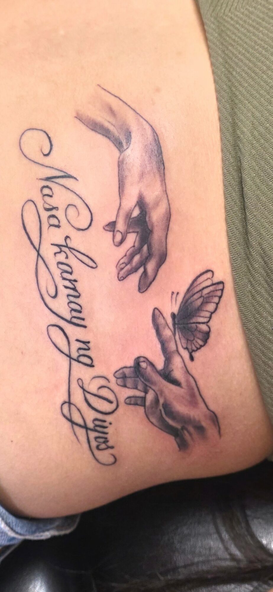 Tattoo of two hands reaching towards each other with cursive text below, on skin. Word count: 20.