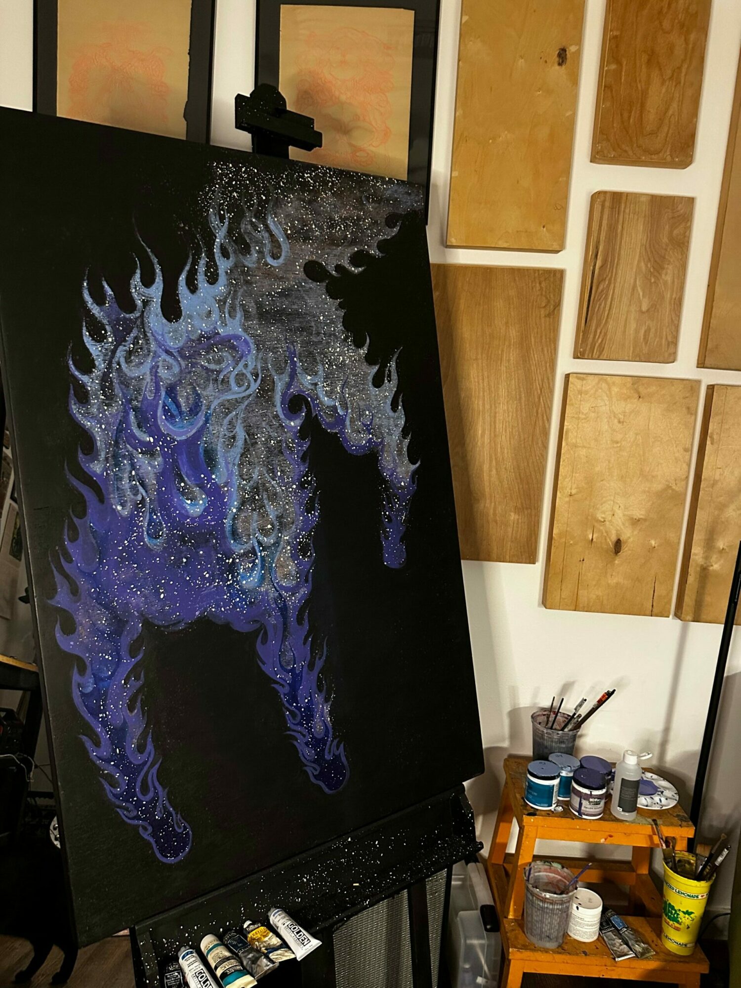 Abstract painting with swirling blue, purple, and white patterns on a black background.