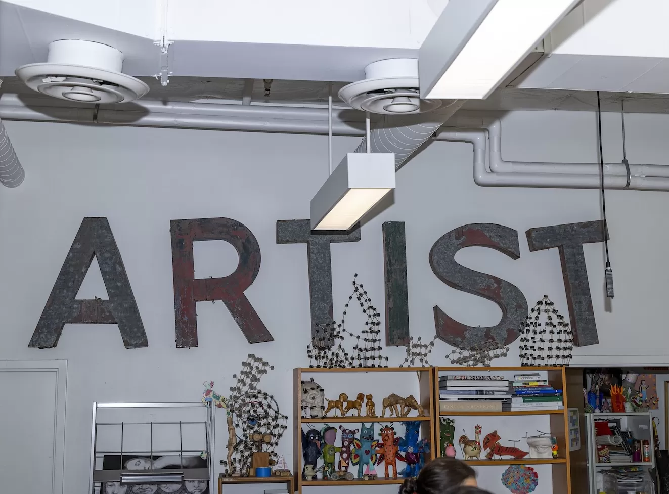 Wall with large painted letters spelling 'ARTIST' and shelves with art supplies and decorations.