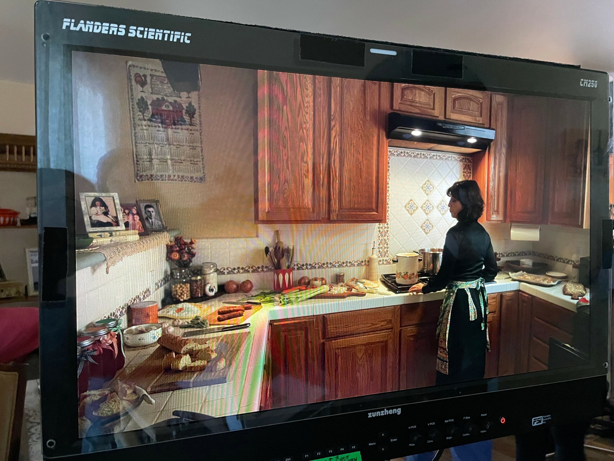 Person cooking in a kitchen with wooden cabinets and a patterned backsplash, seen from the side, with various items on the counter.