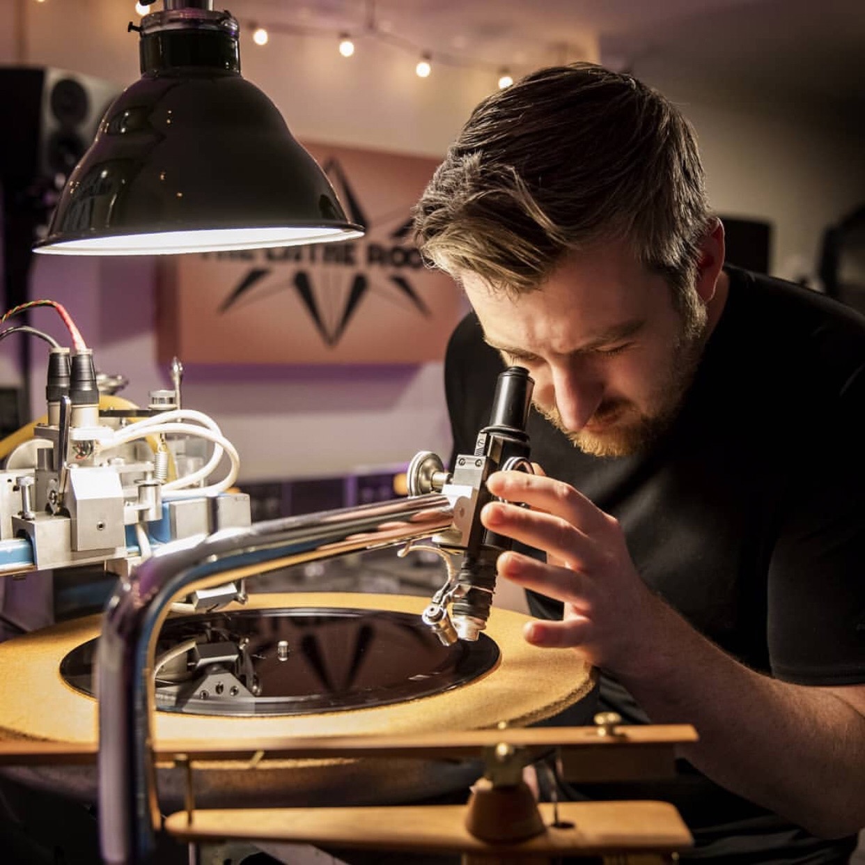 Man looking through a microscope in a laboratory with scientific equipment and a lamp overhead.
