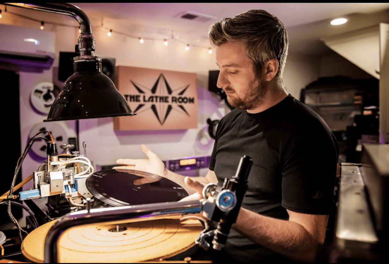 Man working with a turntable in a room with a sign that says 'The Lathe Room'.