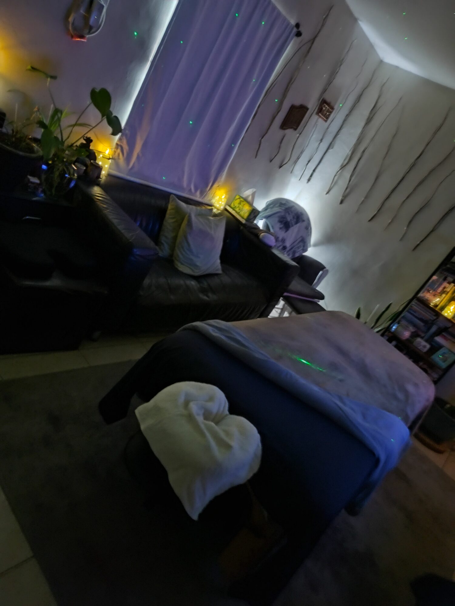 Living room with sofa, cushions, blanket, and decorative lights, viewed from the side.