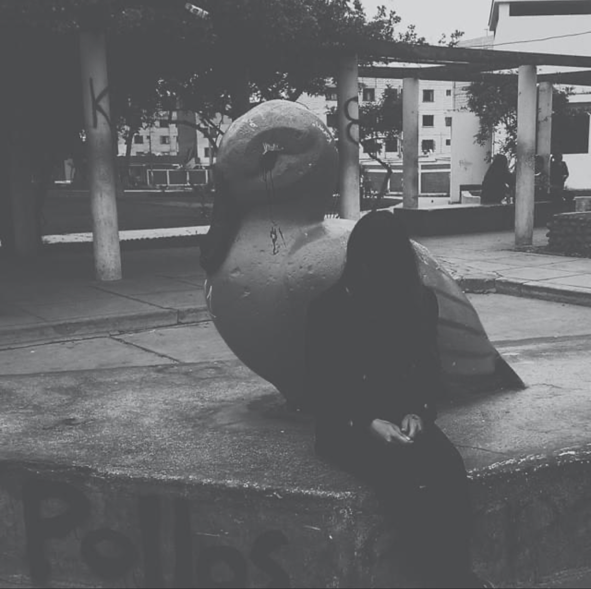 A sculpture of a duck in an outdoor park area with trees and structures in the background.