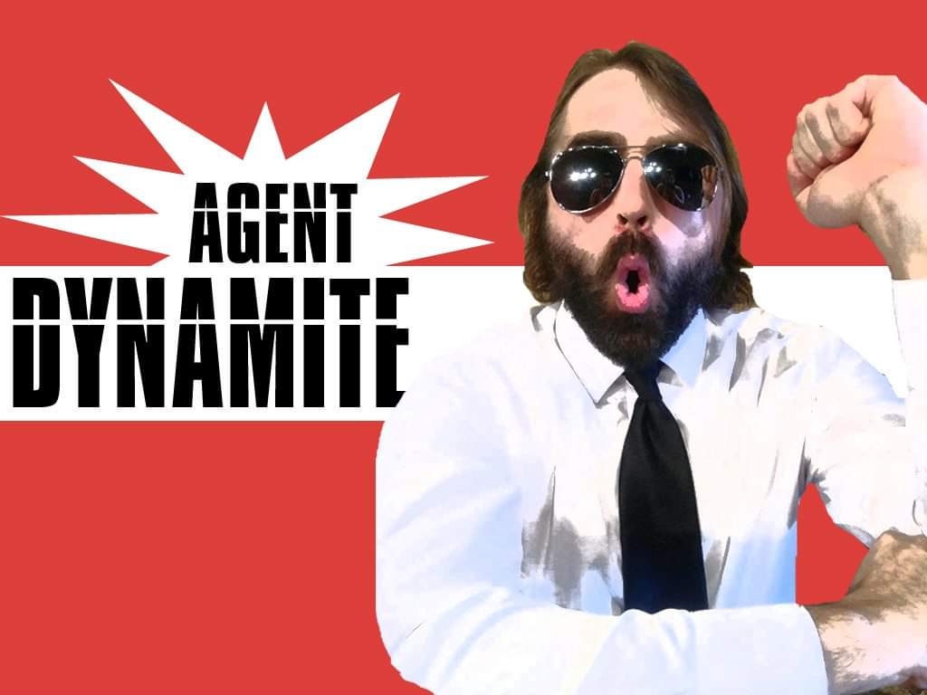 Man with sunglasses and beard, wearing a white shirt and black tie, raising his fist in front of a red background with text.