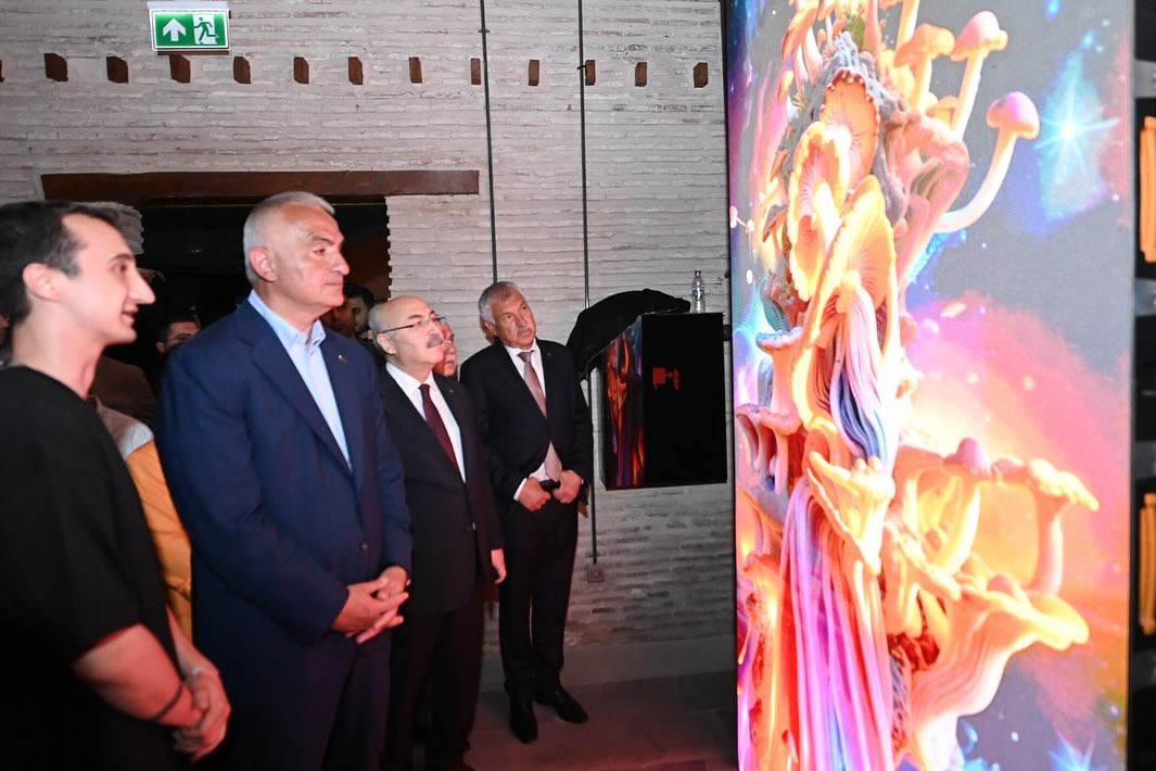Group of five people watching a colorful digital display or artwork in a modern indoor setting.
