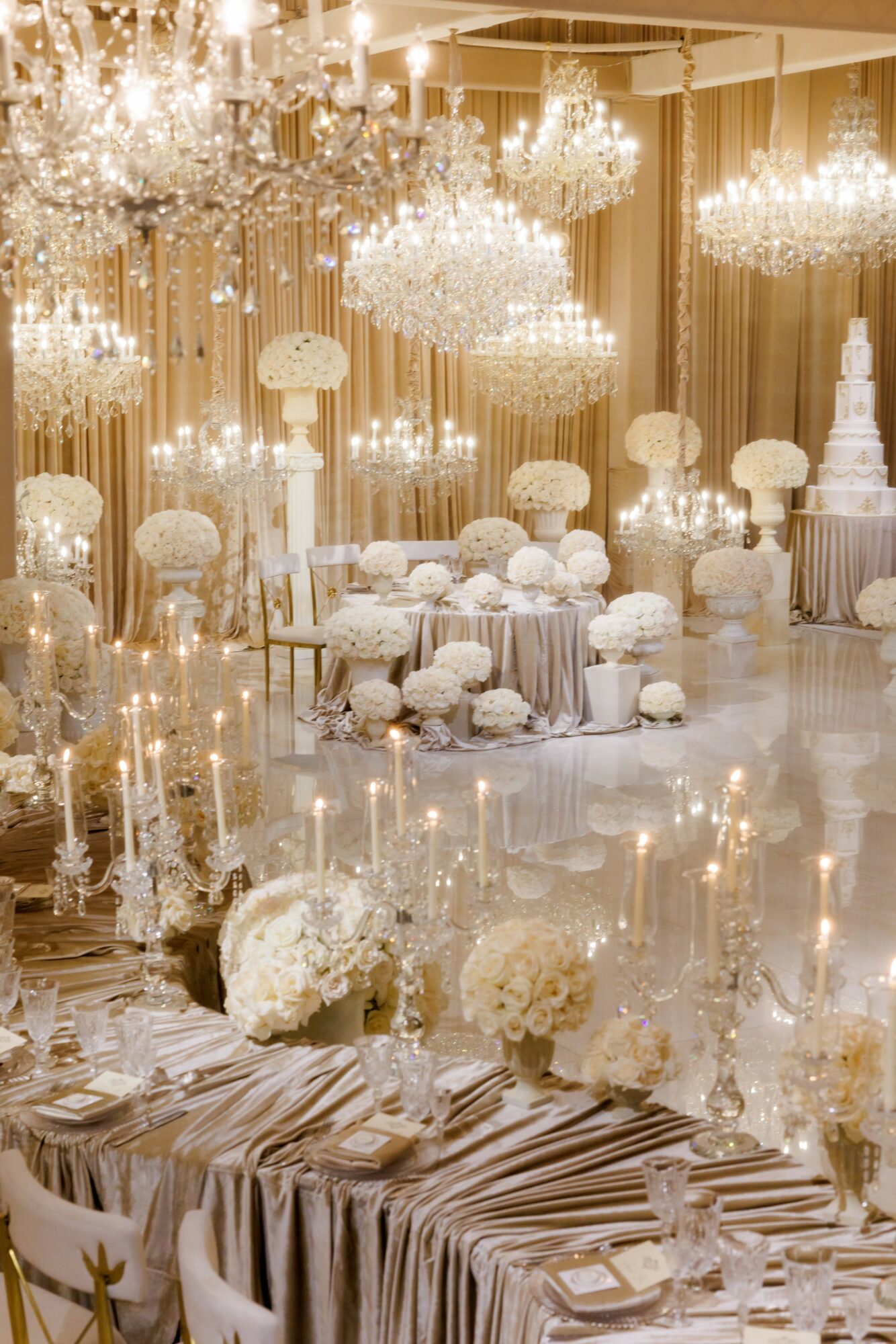 Elegant event space with chandeliers, floral arrangements, and decorated tables for a celebration.
