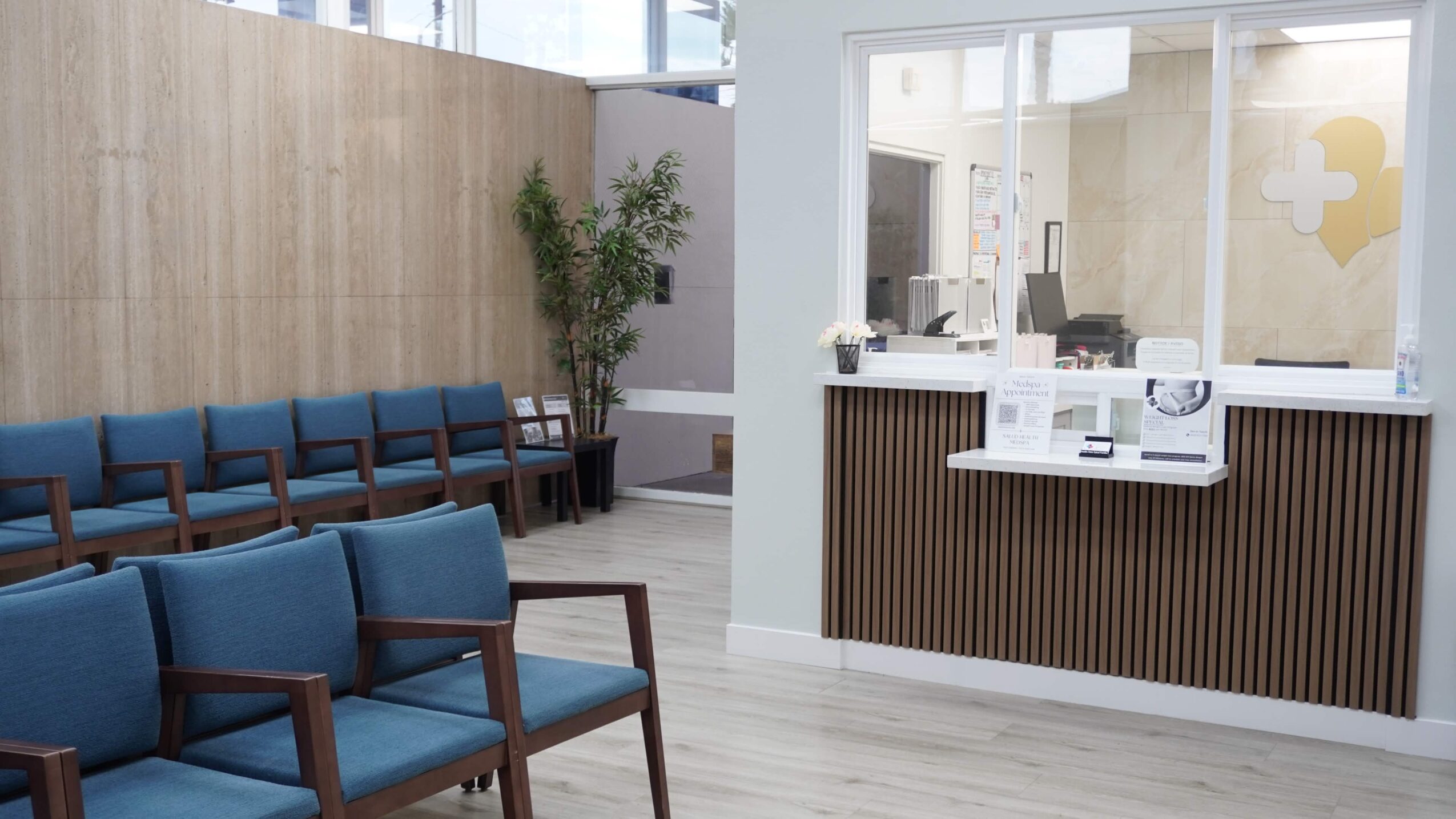 Waiting area with blue chairs, wooden wall, and a reception desk in a modern office space.