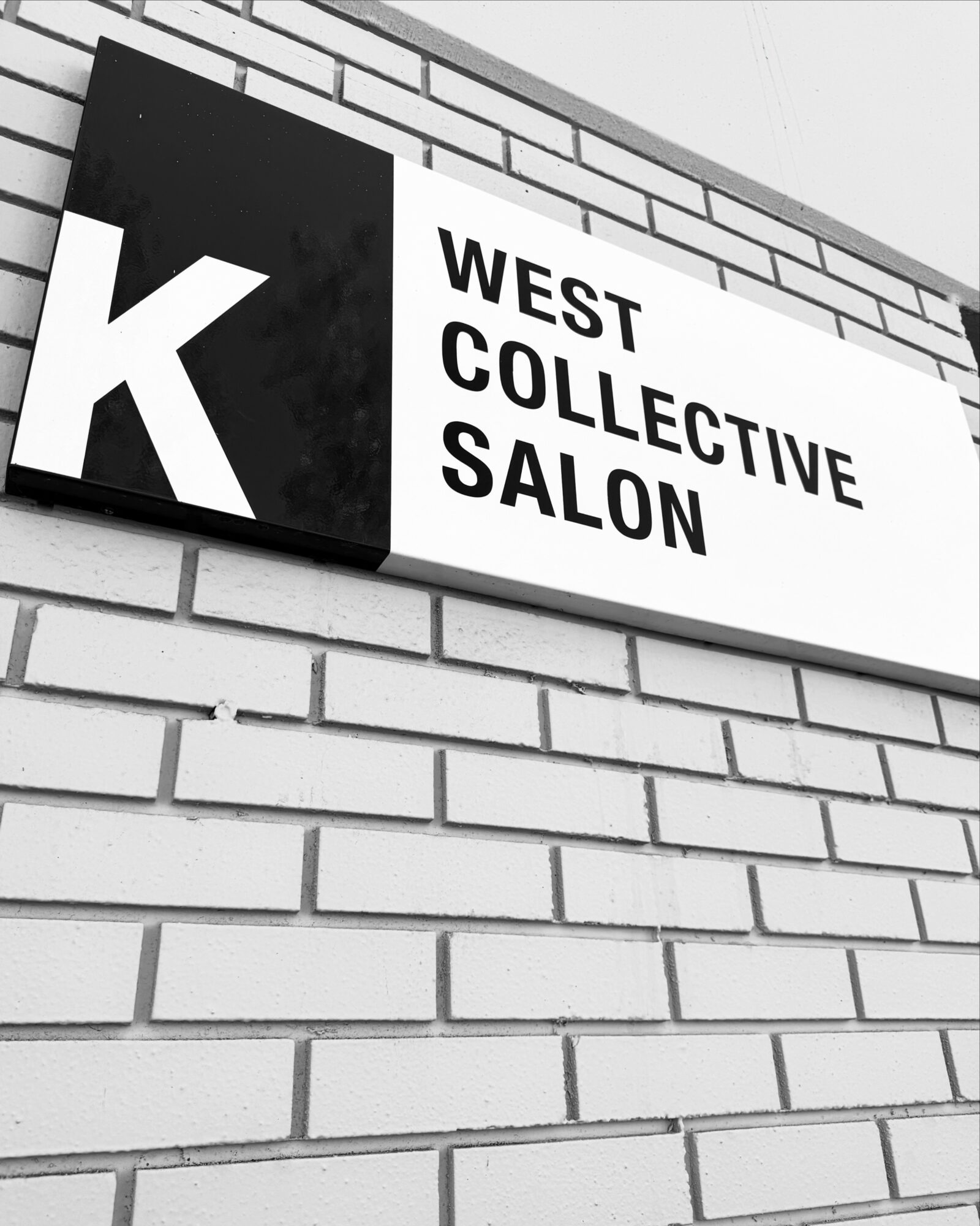 Sign on brick wall reads 'West Collective Salon' with a large letter 'K' on a black background.