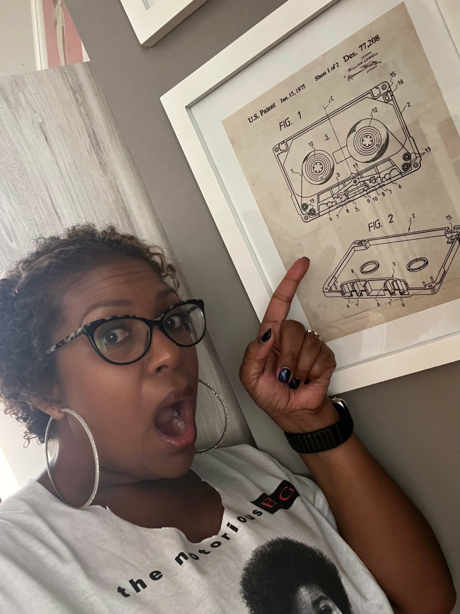 Girl with glasses pointing at technical drawing of a device with two circular components, surprised expression, indoors.
