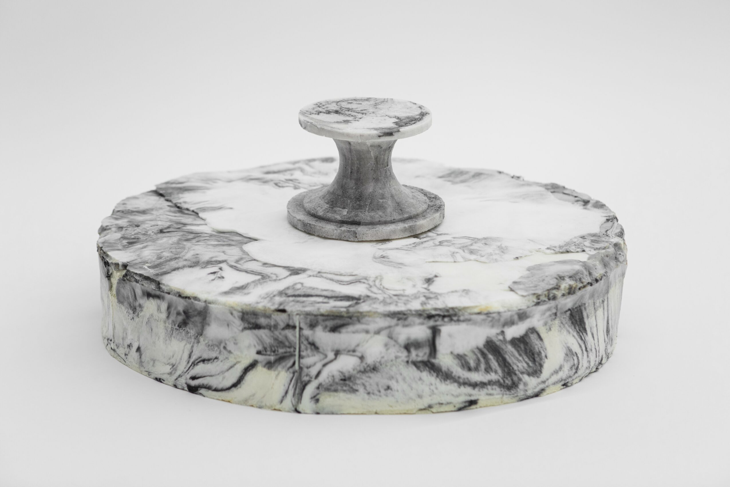 Round marble object with a handle on top, resembling a stamp or seal, on a plain background.